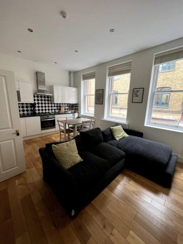 een woonkamer met een zwarte bank en een tafel bij 1-Bed Flat in Historic Camden in Londen