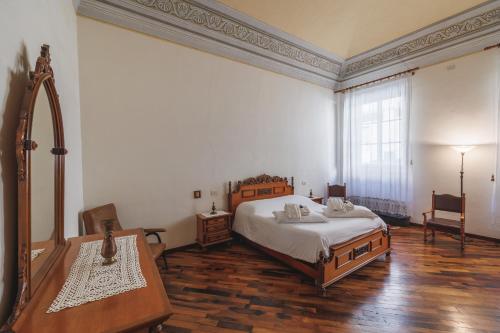 1 dormitorio con cama, mesa y espejo en Casa Livia - Stately house with elevator en Lucignano