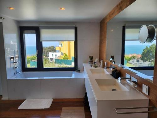 ein Bad mit 3 Waschbecken und einem großen Fenster in der Unterkunft Modern Villa with Sea & River View Pool and Gym. in Lissabon