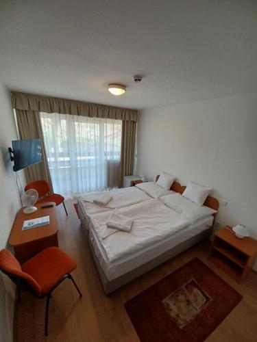 a bedroom with a large white bed and a chair at PSZ Hotel Beach Földvár in Balatonföldvár