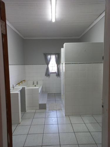 a bathroom with a tub and a sink and a window at Orange Elephant Backpackers in Addo