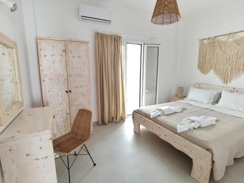 a white bedroom with a bed and a chair at Villa Konstantinos in Perissa