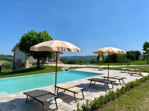 una piscina con sillas y sombrillas junto a ella en Villa Edelia en Mondavio