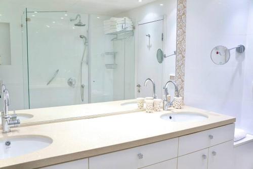 uma casa de banho branca com 2 lavatórios e um chuveiro em Daniel Hotel - Residence Seaside Luxury Flat em Herzeliya