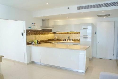a kitchen with white cabinets and a white refrigerator at Daniel Hotel - Residence Seaside Luxury Flat in Herzelia 