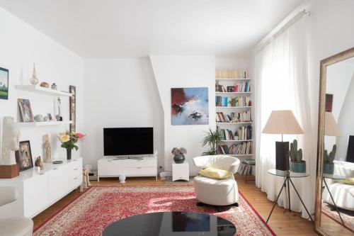 un salon blanc avec une télévision et un canapé dans l'établissement Spacious apartment on the outskirts of Paris, à Levallois-Perret