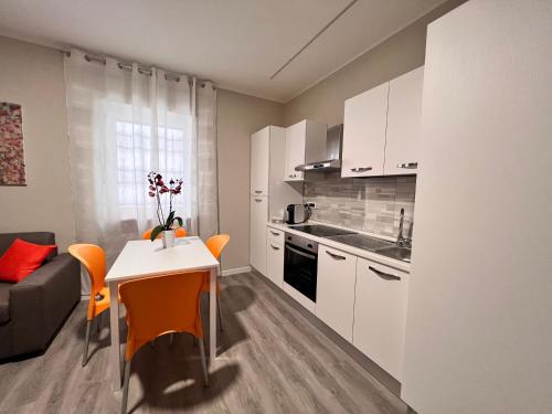 uma cozinha com armários brancos e uma mesa com cadeiras laranja em Helios em San Giovanni Rotondo