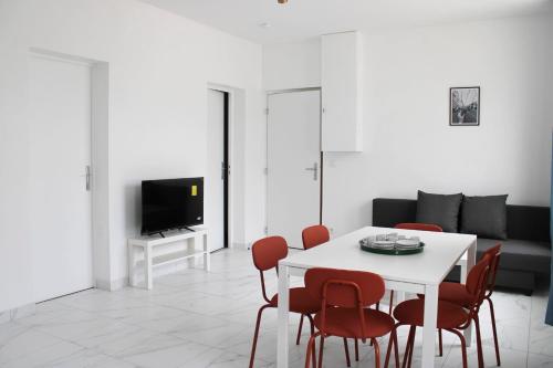 ein Wohnzimmer mit einem weißen Tisch und roten Stühlen in der Unterkunft Newly renovated cocoon with terrace near the Seine in Ivry-sur-Seine