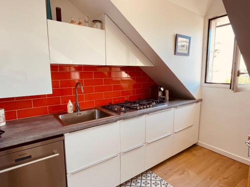 Il comprend une cuisine avec un évier et un mur en briques rouges. dans l'établissement **La Bretonnerie, bel appartement de standing, à Concarneau