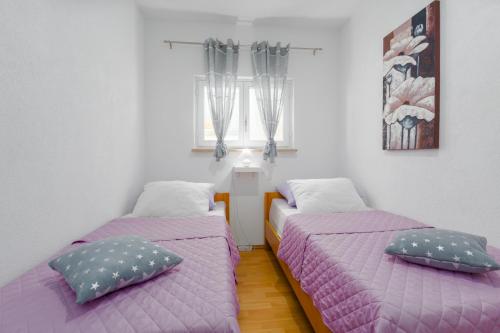 two beds in a room with purple sheets and pillows at Family Apartment Romina in Vrsar