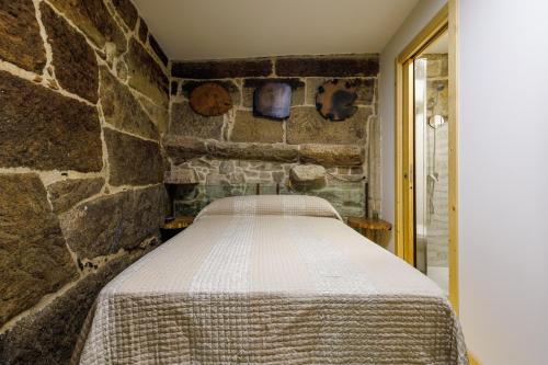 Bett in einem Zimmer mit einer Steinmauer in der Unterkunft A de Calón in Marín
