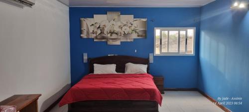 um quarto azul com uma cama com um cobertor vermelho em Beautiful Villa with Swimming Pool in Assinie em Mafia