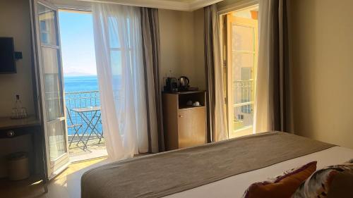 a bedroom with a large bed and a large window at Hôtel Des Gouverneurs in Bastia