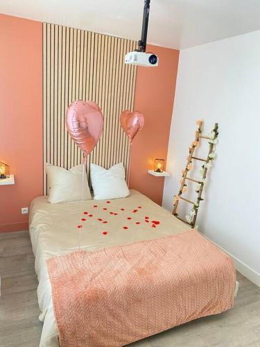 Una habitación con una cama con corazones rosados y globos en Maison vue sur mer en Bretteville
