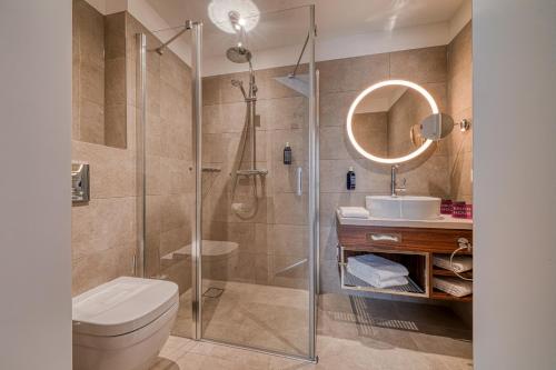 a bathroom with a shower and a toilet and a sink at FourSide Hotel Ringsheim in Ringsheim