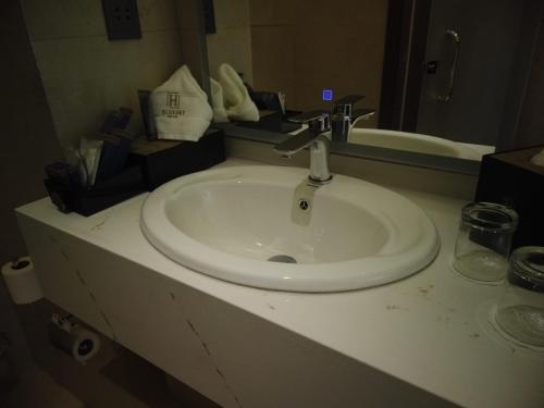 H Luxury Hotel في وادي موسى: منضدة الحمام مع الحوض والمرآة