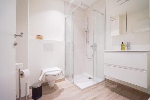 een witte badkamer met een douche en een toilet bij Casa Grande 28 I Studio with Lake View in Sekull