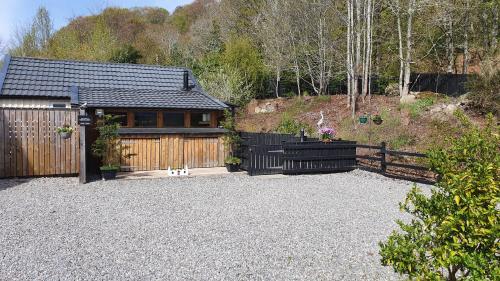 a house with a fence and a gravel driveway at Herons Rest in Drumnadrochit