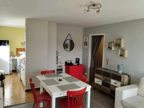 een keuken en een woonkamer met een witte tafel en rode stoelen bij Appartement les Rousses Bien situé in Les Rousses