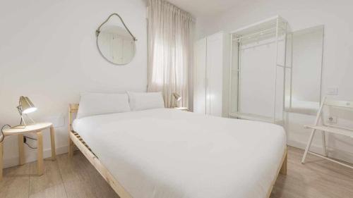 a white bedroom with a large bed and a window at Apartamentos Dimax by Toledo AP in Toledo