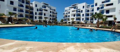 a large swimming pool with blue water in front of buildings at COSTA MAR MARTIL TETOUAN in Martil