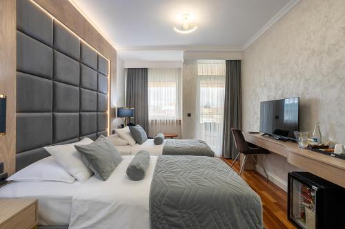 a hotel room with two beds and a desk at A Hoteli - Hotel Izvor in Arandjelovac