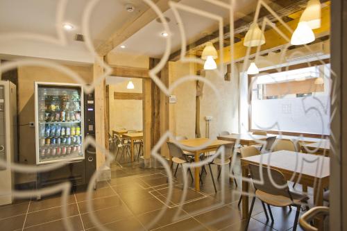 een restaurant met tafels en stoelen en een koelkast bij El Albergue de la Catedral in Vitoria-Gasteiz