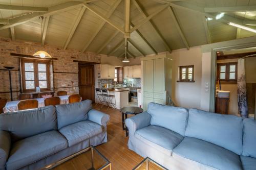 ein Wohnzimmer mit blauen Sofas und eine Küche in der Unterkunft Villa Korfes-Κορφές Τριώροφη Βίλα για Οικογένειες και Παρέες in Karpenisi