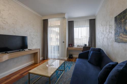 a living room with a blue couch and a tv at A Hoteli - Hotel Izvor in Arandjelovac