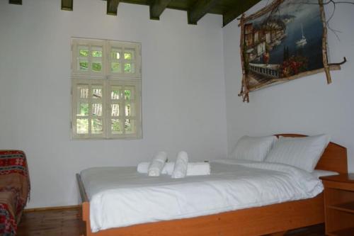 a bedroom with a white bed with a window at Cabanita in Întorsura Buzăului