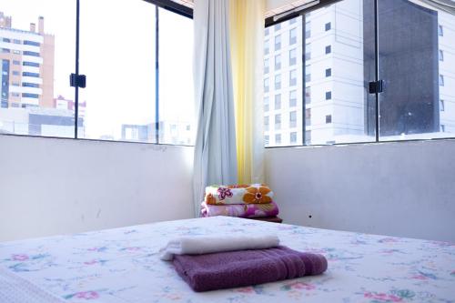 a bedroom with a bed and a large window at Apartamentos na região Central Cobertura e 2 quartos in Ponta Grossa