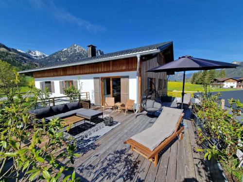 a wooden deck with a couch and an umbrella at Alpenchalet Vils Tirol in Vils