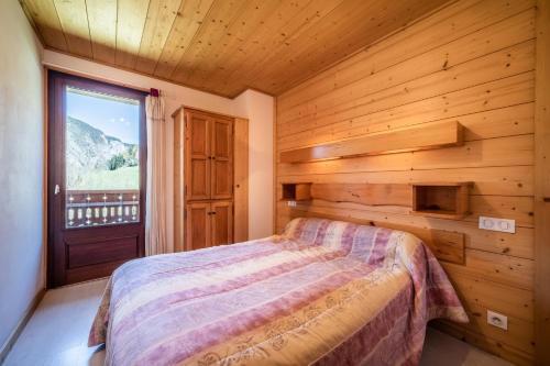 a bedroom with a bed and a large window at Apt Chénives 2 - Morzine in Morzine