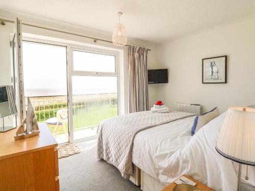 a bedroom with a bed and a large window at Gull Cottage in Lowestoft
