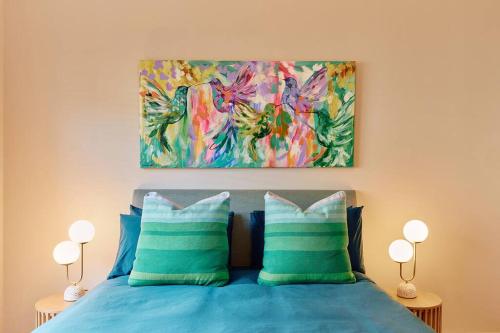 1 dormitorio con 1 cama con 2 almohadas azules y una pintura en Vine Close Apartment, en Healesville