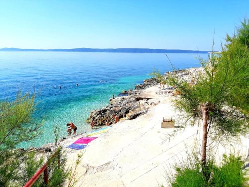 a sandy beach with people swimming in the ocean at Apartment Anita in Trogir
