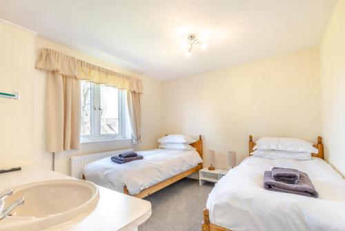 two beds in a room with a sink and a tub at Elvington Cottage - Family-friendly cheerful house at the heart of the Cotswolds in Bourton on the Water