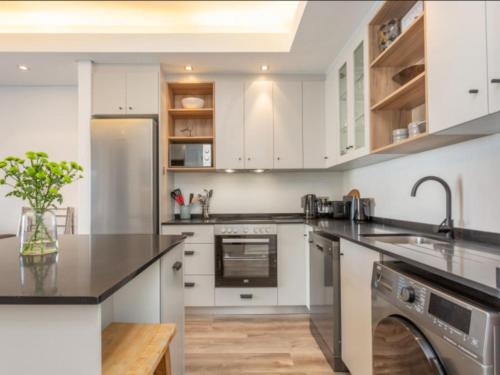 eine Küche mit weißen Schränken und einer schwarzen Arbeitsplatte in der Unterkunft Edgy On Bree in Kapstadt