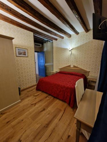 a bedroom with a red bed and a wooden floor at Hotel Tintoretto in Venice