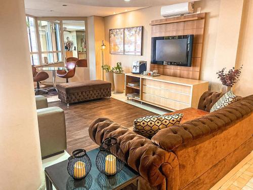 a living room with a couch and a flat screen tv at Diaudi Hotel in São José