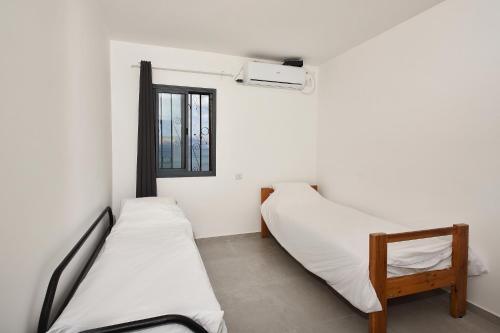 two beds in a room with a window at Levication Multiple Apartments - Family Stays Tiberias in Tiberias
