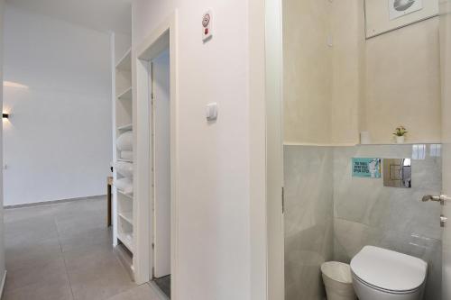 a white bathroom with a toilet and a closet at Levication Multiple Apartments - Family Stays Tiberias in Tiberias