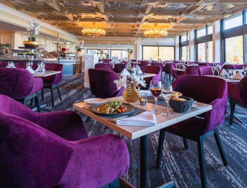 a dining room with purple chairs and a table with wine glasses at PLAZA Premium Timmendorfer Strand in Timmendorfer Strand