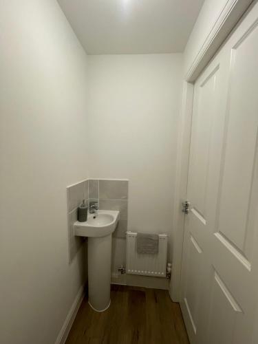 a white bathroom with a sink and a door at Barry Waterfront Stays - ENTIRE 3 BED PROPERTY in Barry