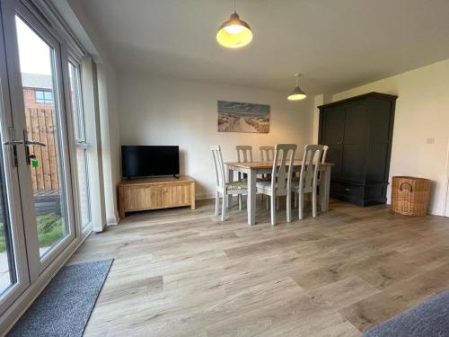 a dining room with a table and chairs and a television at Barry Waterfront Stays - ENTIRE 3 BED PROPERTY in Barry