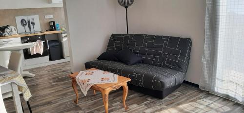 - un canapé noir dans le salon avec une table dans l'établissement Logement au pied de la Montagne de Ceuse, à Sigoyer