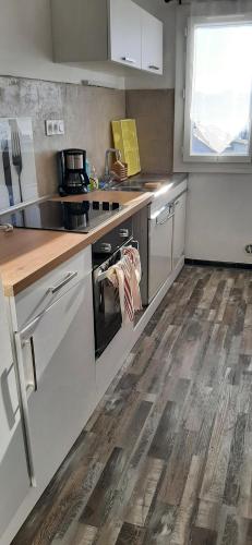 a kitchen with white appliances and a wooden floor at Logement au pied de la Montagne de Ceuse in Sigoyer