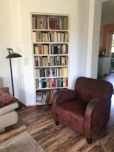 a living room with a chair and a book shelf with books at Wohlfühloase Dresden Nickern in Dresden