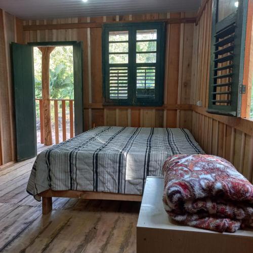 a bedroom with a bed in a room with wooden walls at Sítio Vô Luizinho in Nova Trento