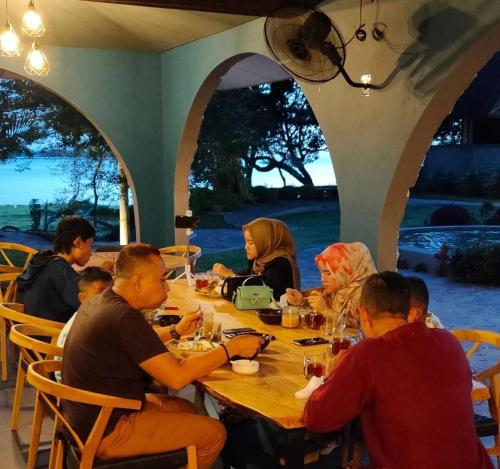 een groep mensen die rond een houten tafel zitten bij La Collina Villa in Jepara